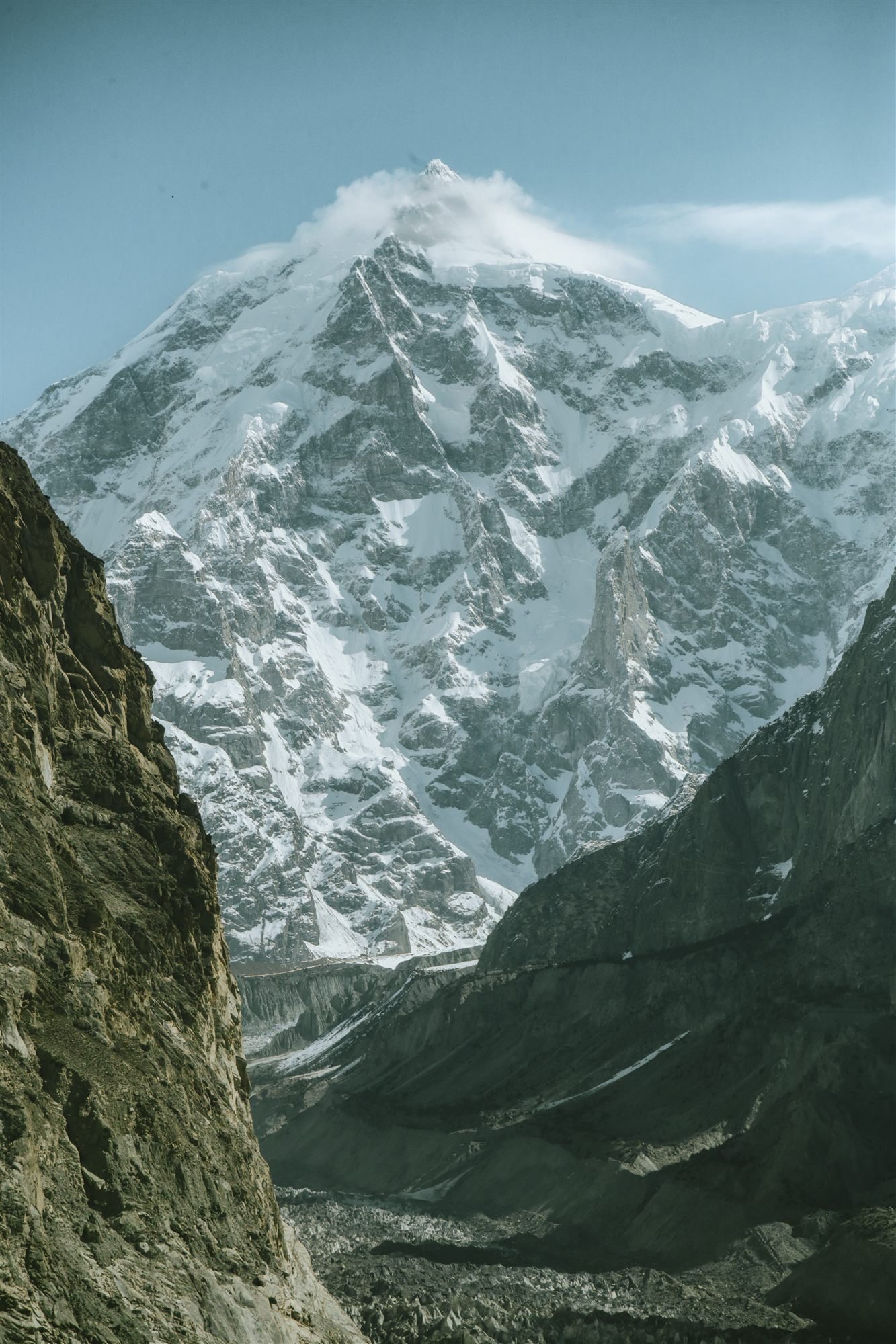 A street in Upper Hunza lined with shops and cafes, mountains behind