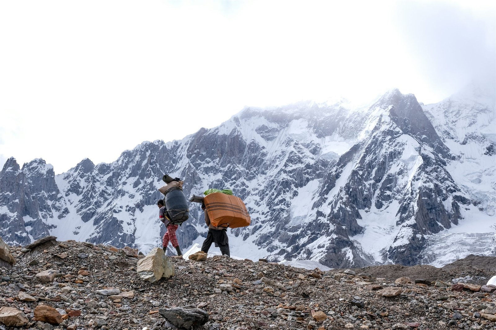A line of porters carrying loads across the Baltoro glacier