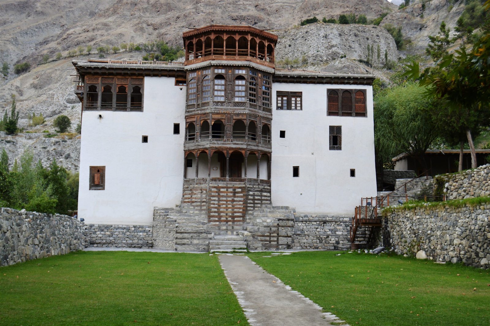 The full facade of Khaplu Fort framed by mountains and lawn