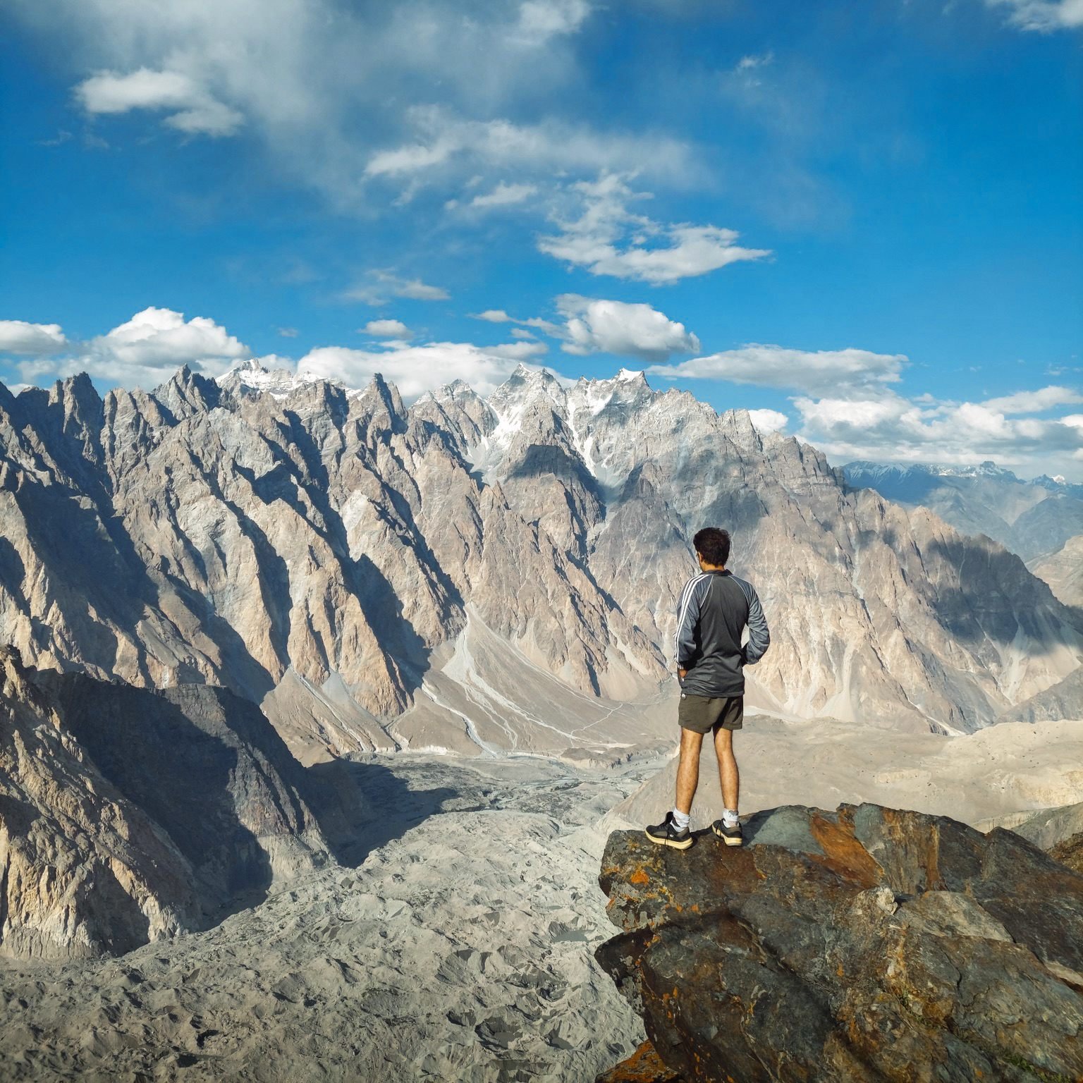 A hiker looking down at the Passu Glacier from a ridge above